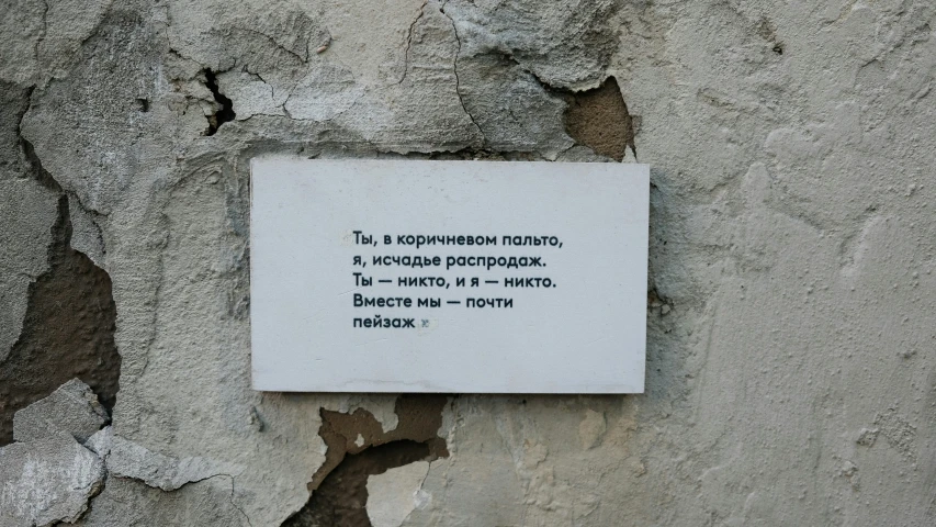 a small sign is placed against a dirty wall