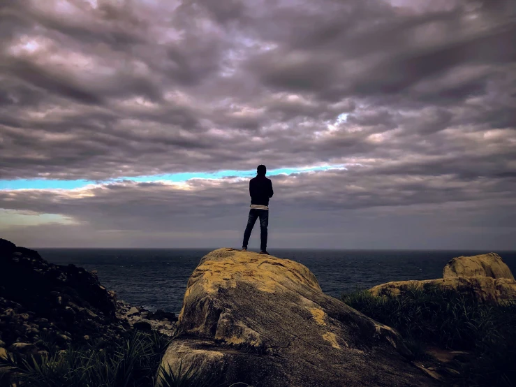 a man standing on top of a rock near the ocean