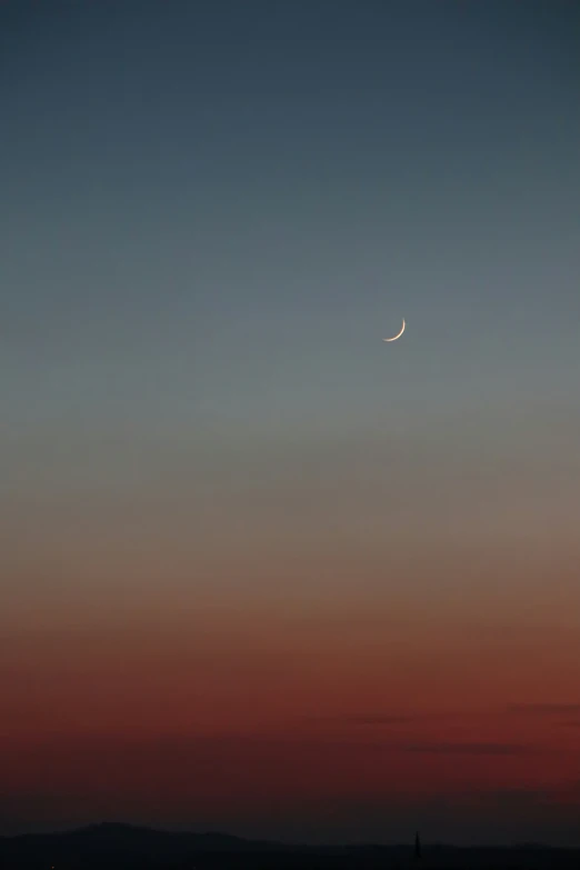 the crescent shines in the blue sky at dusk