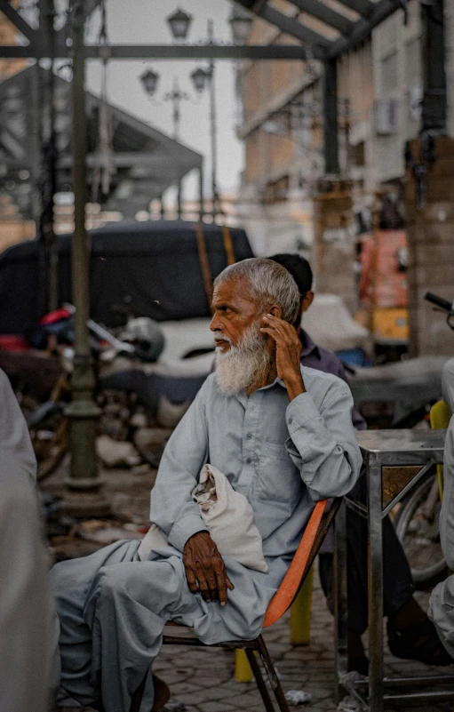 the older man is sitting on his phone