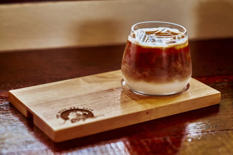 a glass full of liquid on top of a wooden tray