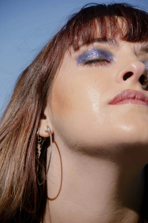 woman wearing earrings in front of blue sky