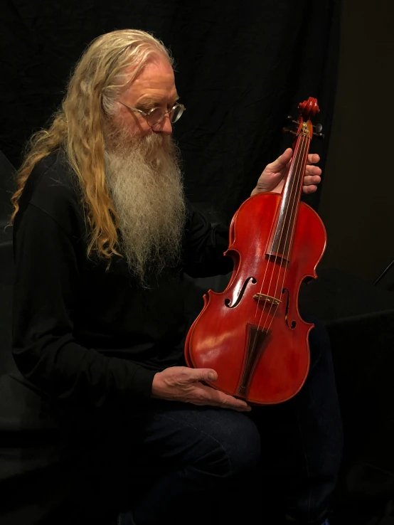 an older man sitting and holding a violin