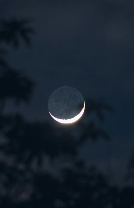 a crescent moon seen through the cloudy sky