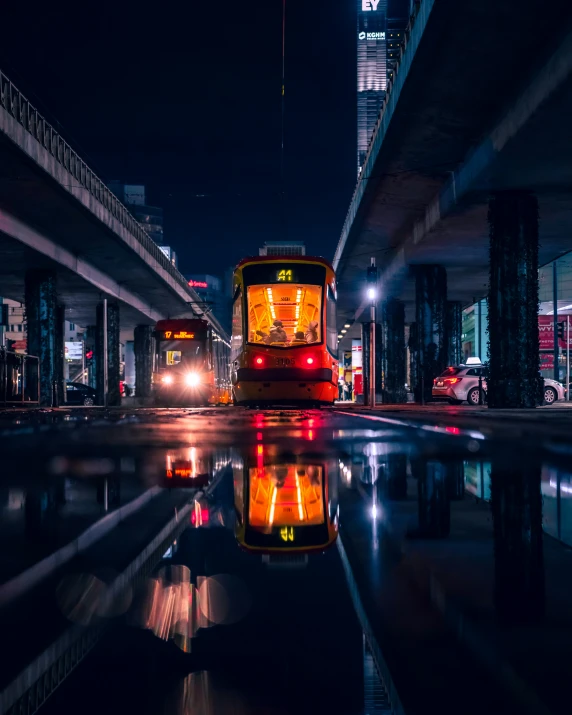 a street car driving under a bridge with the lights on at night