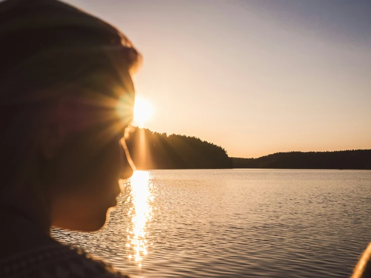 a man looks into the distance while sitting in a boat at sunset