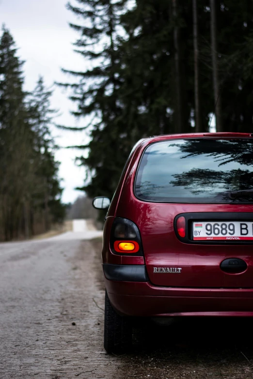 a small red car parked by a forest