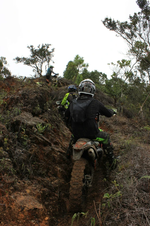 man on dirt bike making steep trail next to trees