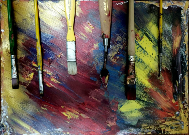 painting brushes and a paint brush hanging from an abstract background