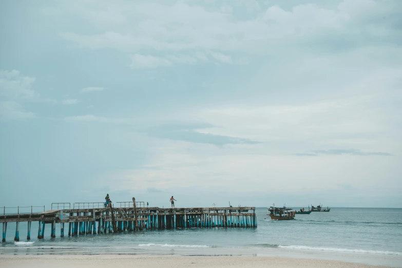 a wooden pier with fishing boats at it on a body of water