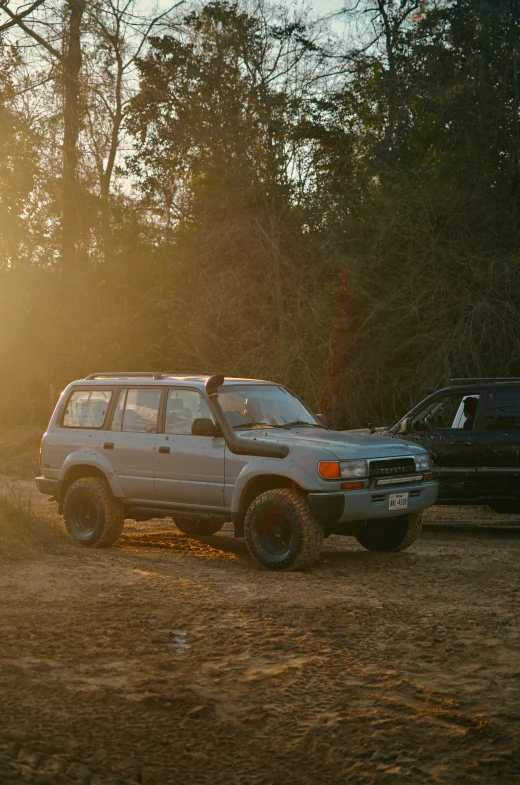 there are two cars parked next to each other in the dirt