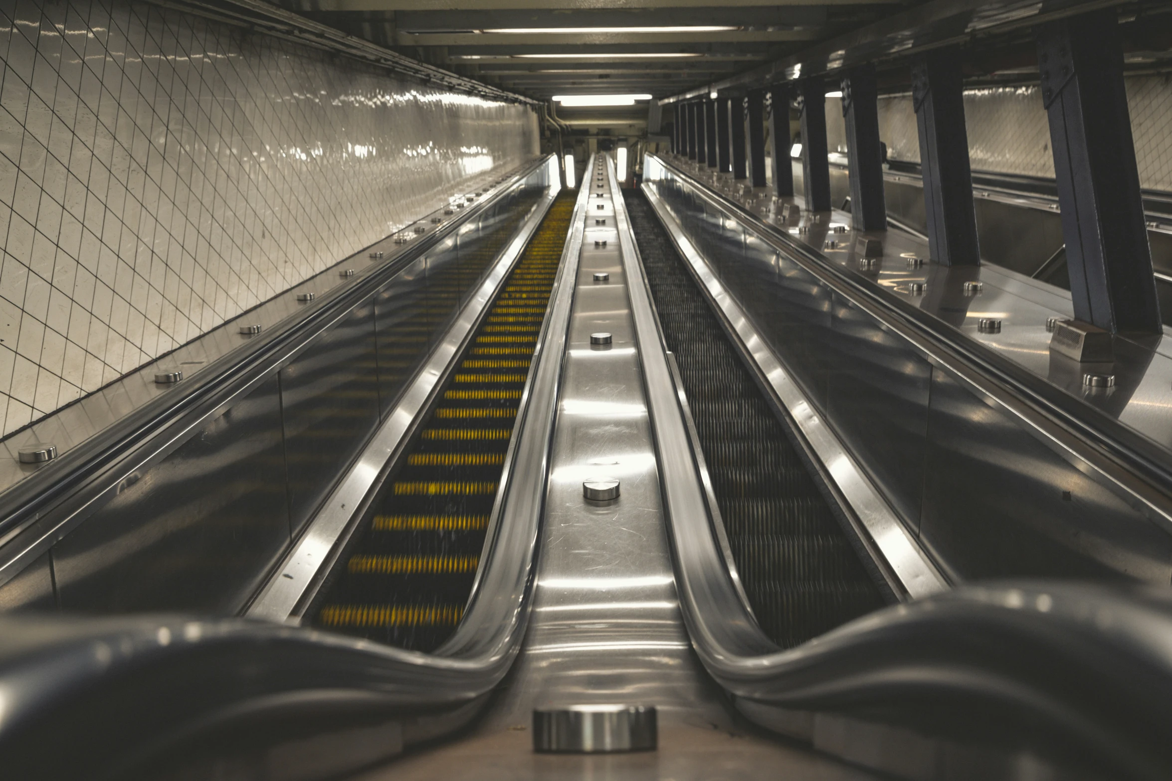 an escalator with lots of yellow lights in a building