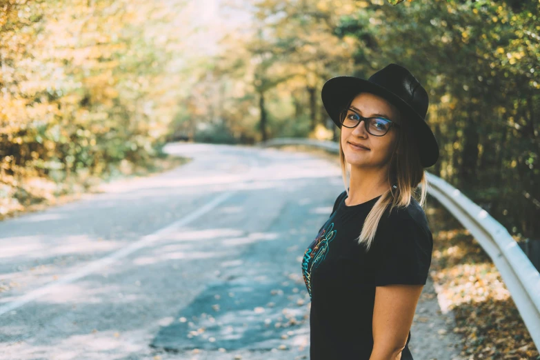 a woman with a hat is standing on the side of the road