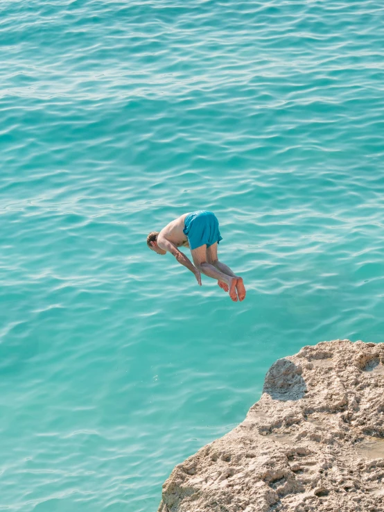 a man diving into the water from a cliff