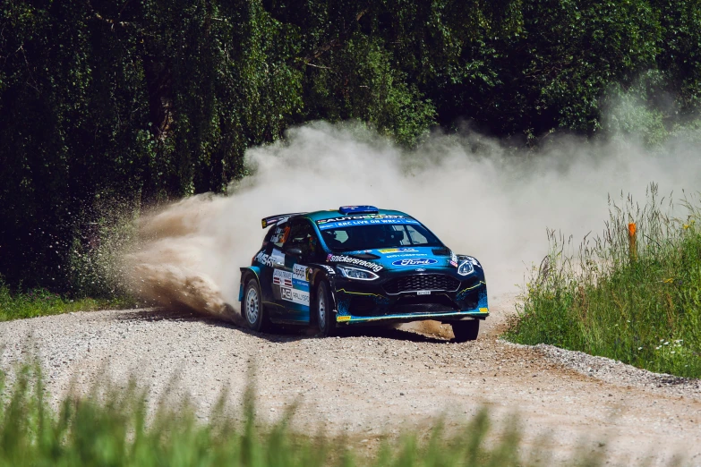 a car driving on a gravel road through some trees