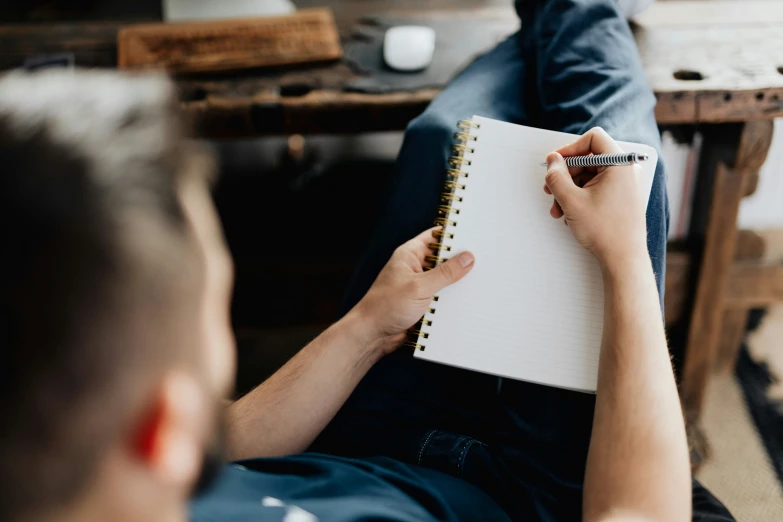 someone sits on the floor and holds a notebook with pen