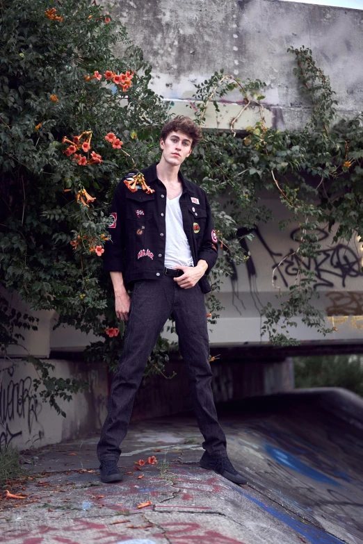 a boy posing for a picture next to graffiti