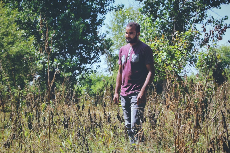 a man standing in tall grass looking away from the camera