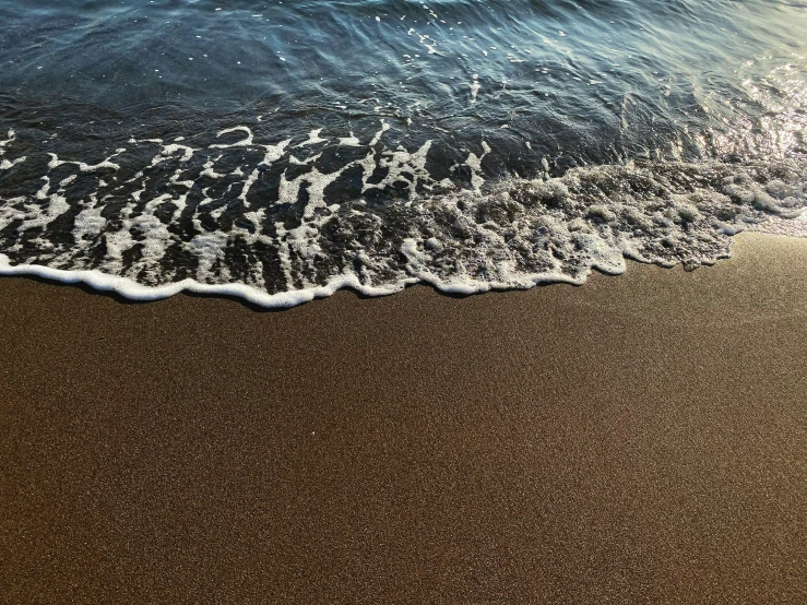an ocean waves on the sandy beach near the shore