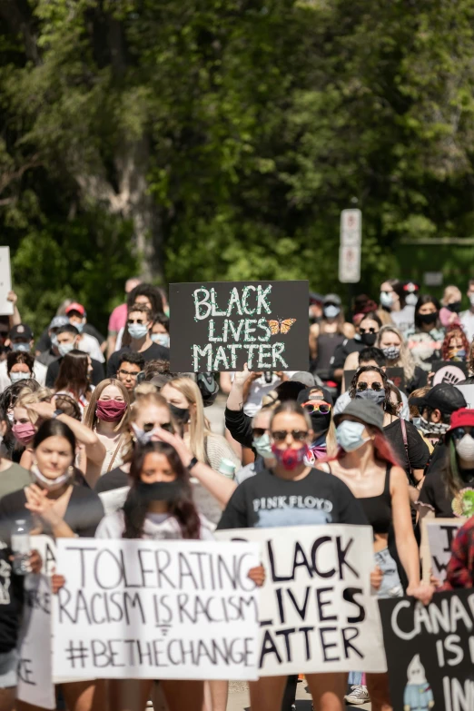 some people protesting on a crowded sidewalk with signs