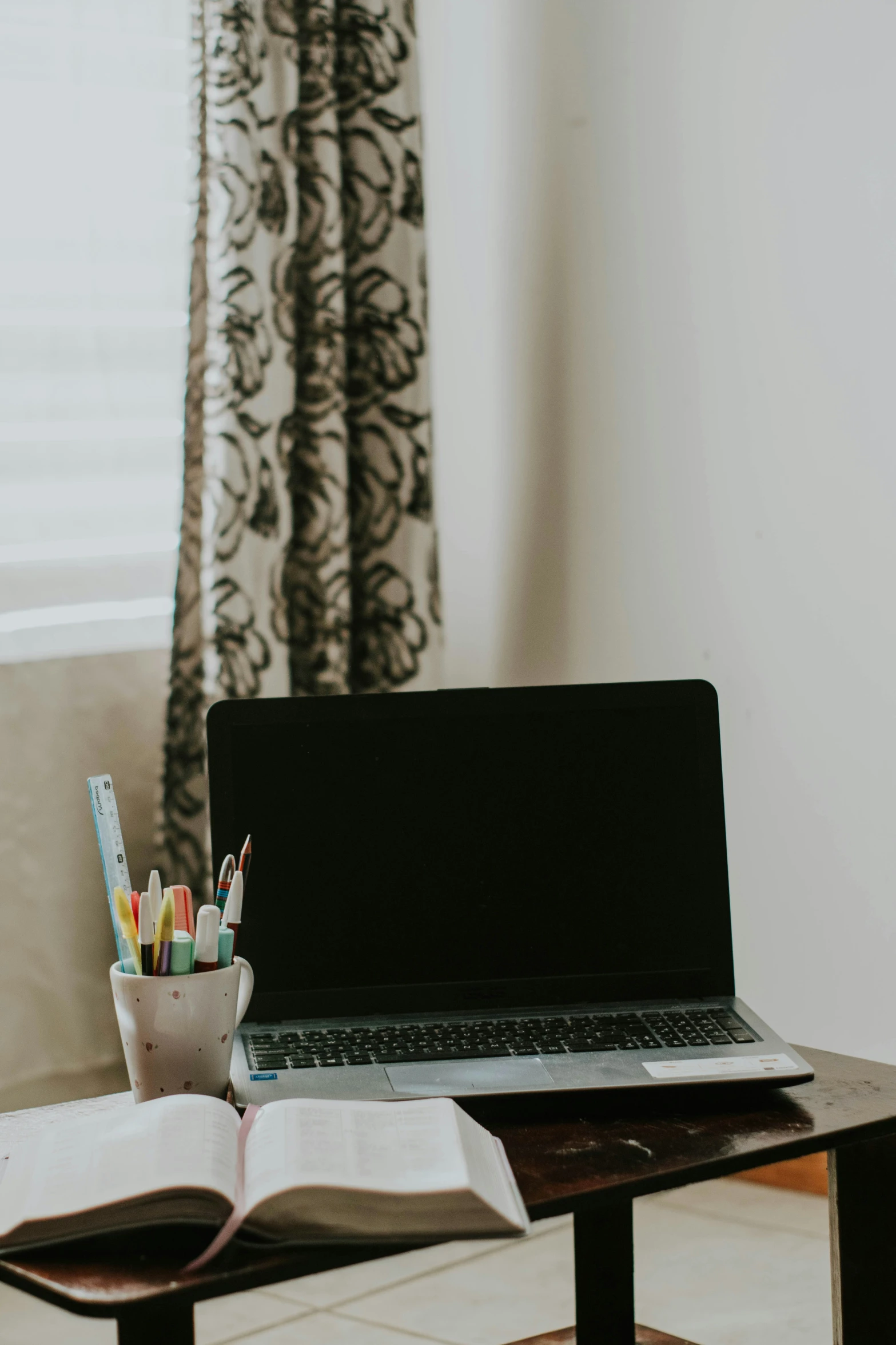 a desk with some notebooks, pens and a laptop