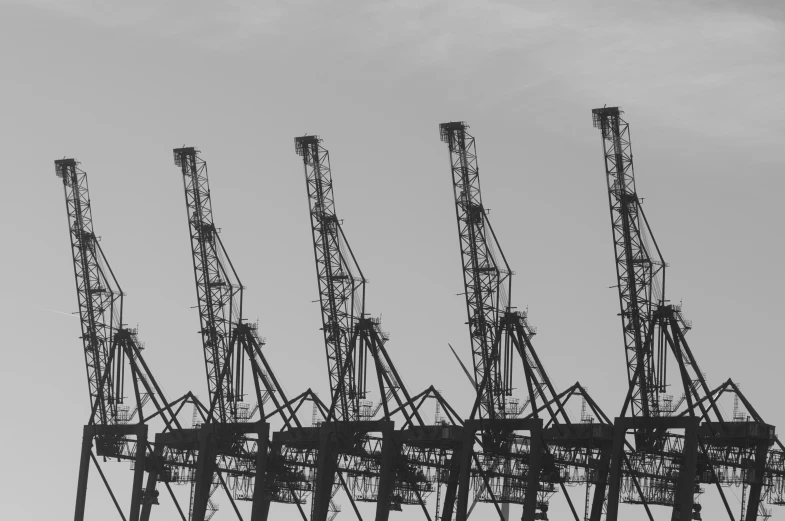 the crane towers in a large field stand out against the sky