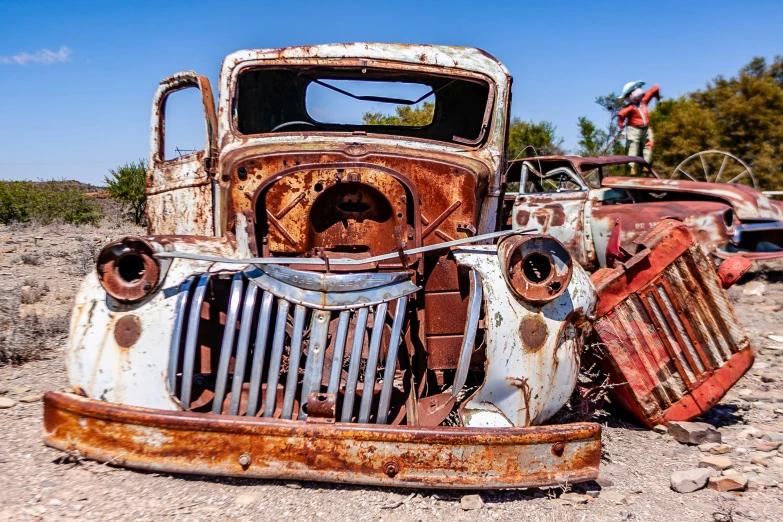 several cars sitting on a dirt road with blue sky in the background