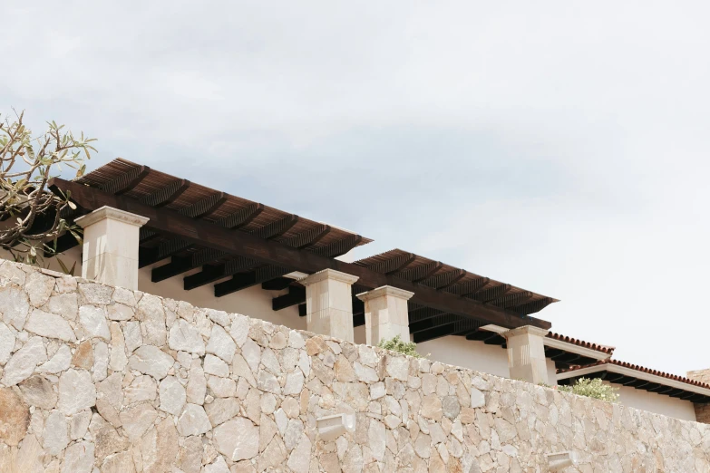 a row of brown roof with two pillars on top of a stone wall