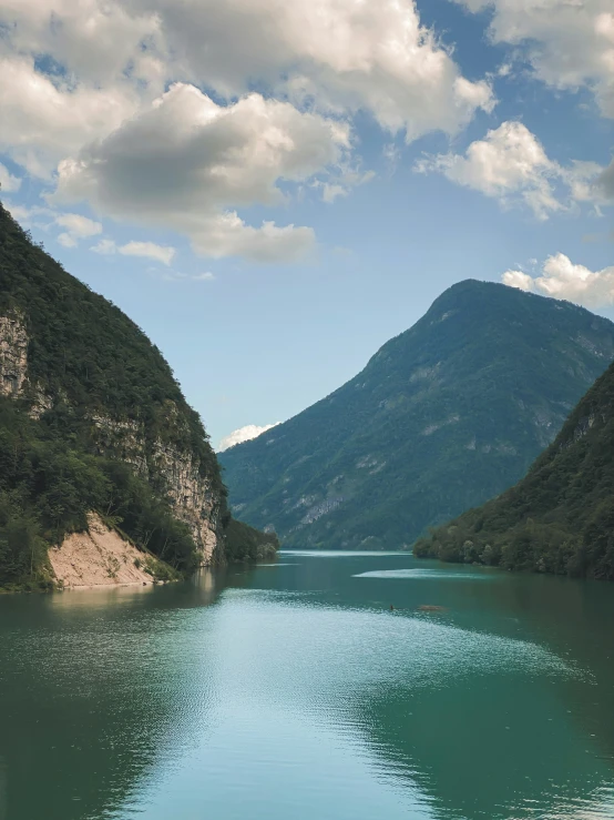 a river is next to some mountains under a cloudy sky