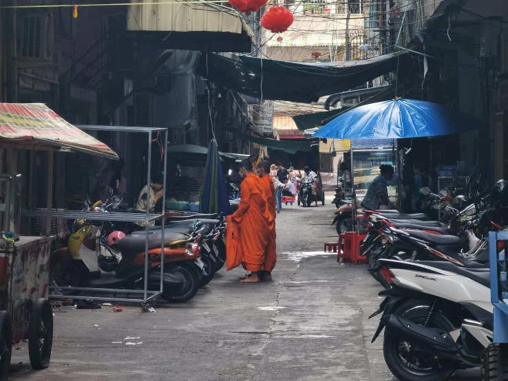 a monk in orange walking through an alley