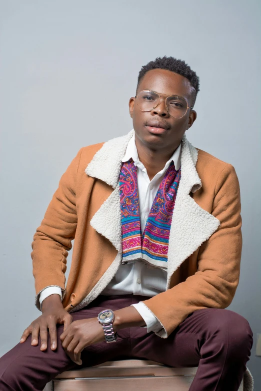 a man sits in front of a wall while wearing glasses