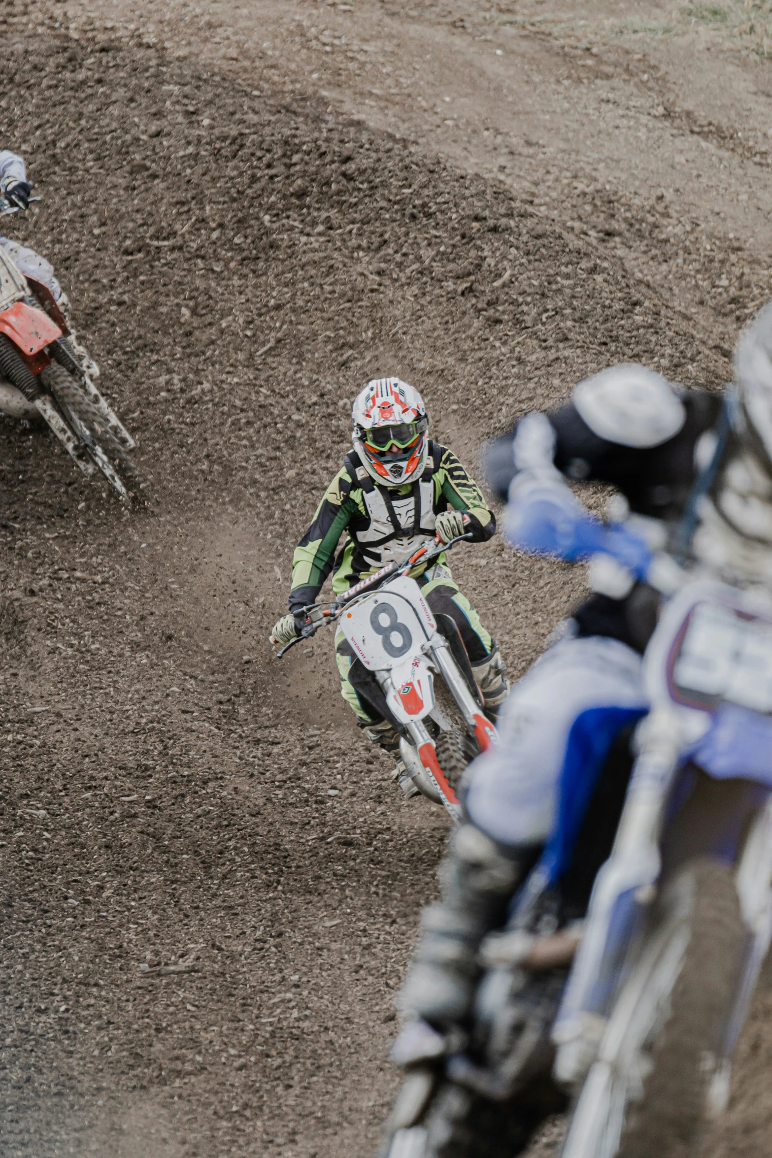 two people are racing motorcycles on a dirt track