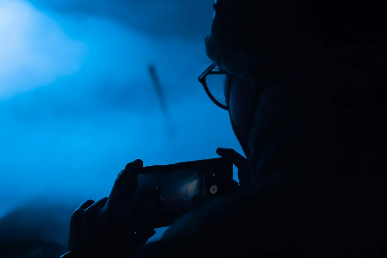 silhouetted person taking a po with dark lighting