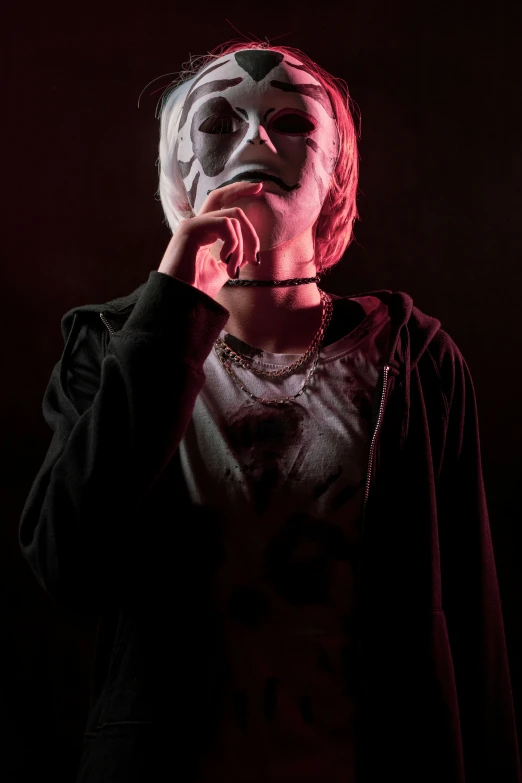 an asian boy in a scary mask is standing against a dark background