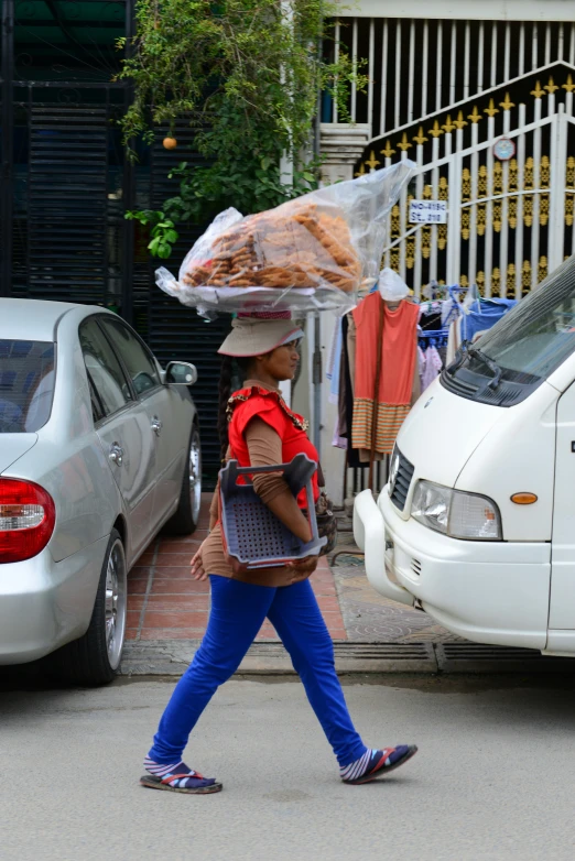woman walking down street carrying food on her head