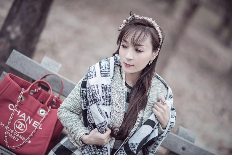 a woman is sitting on a park bench and looking at her phone