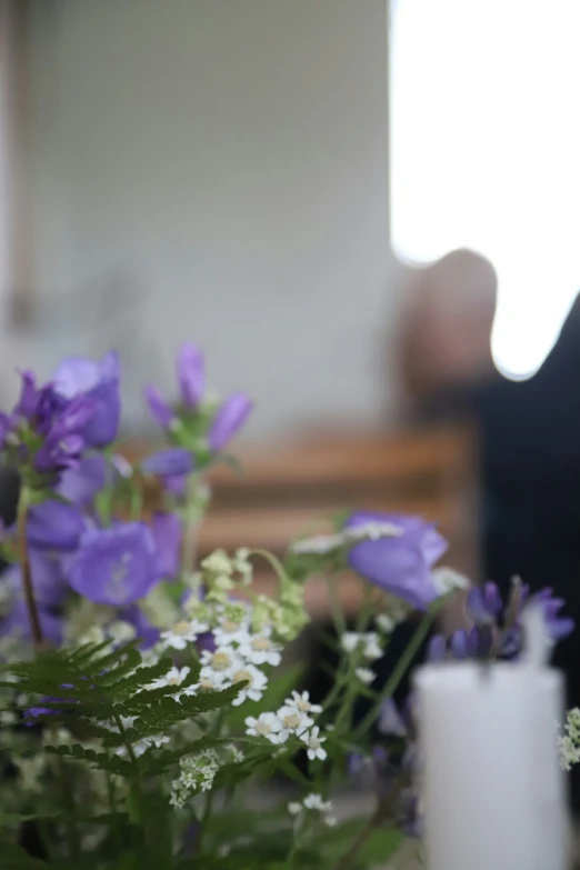 purple and white flowers in vase next to small candle