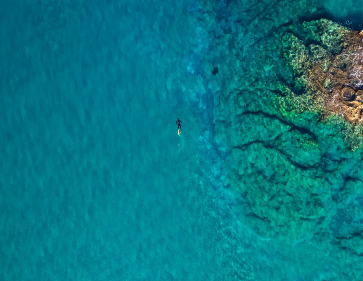 a person paddling their boat in clear water near rocks