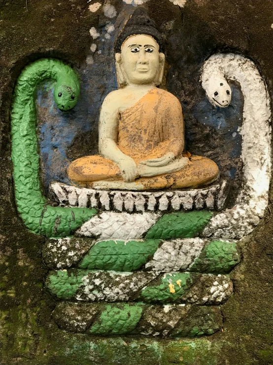 a painted statue of buddha with a snake on his body