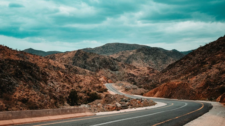 an empty street surrounded by rocky mountains