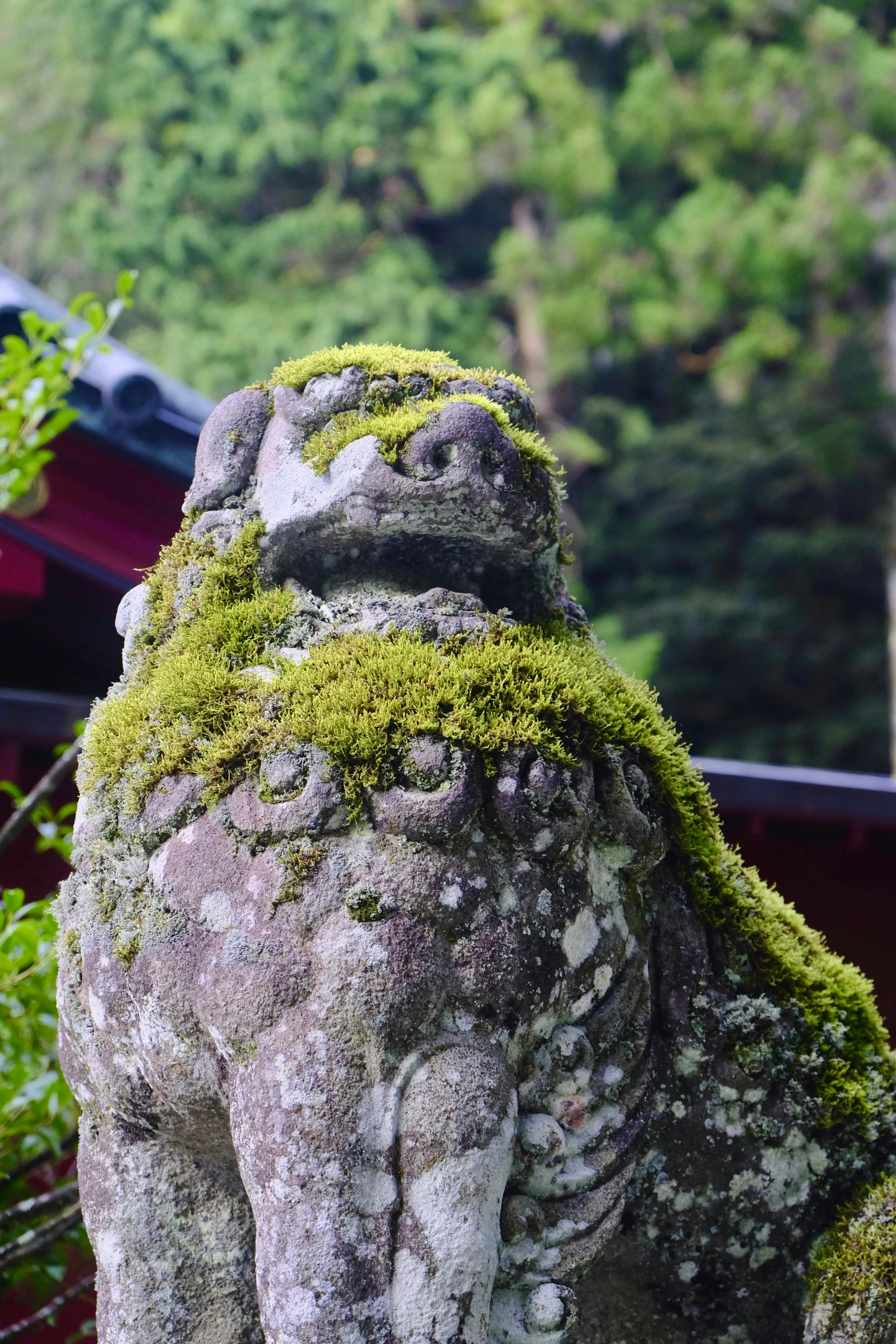 a stone animal statue covered in moss with a tree nearby