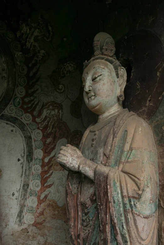 a stone statue standing next to a large mirror