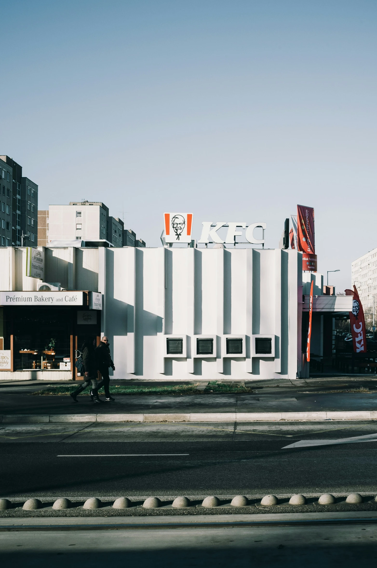 a building made out of white brick sits in front of a street