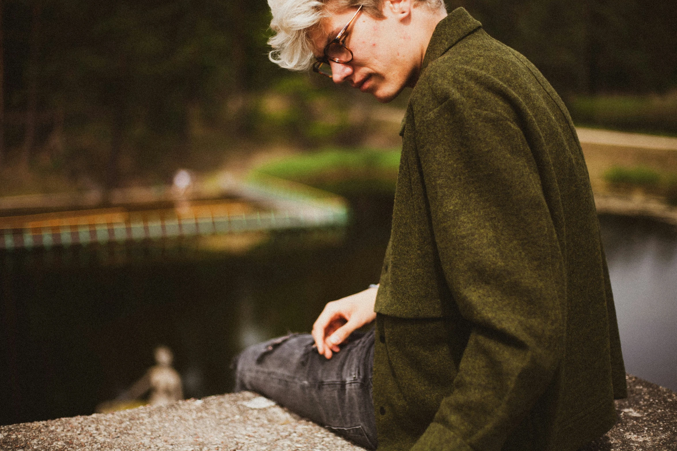 an older man sitting on a rock looking down