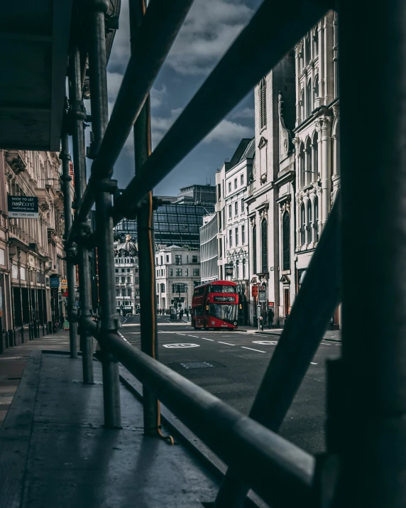 a red bus and some buildings and a fence