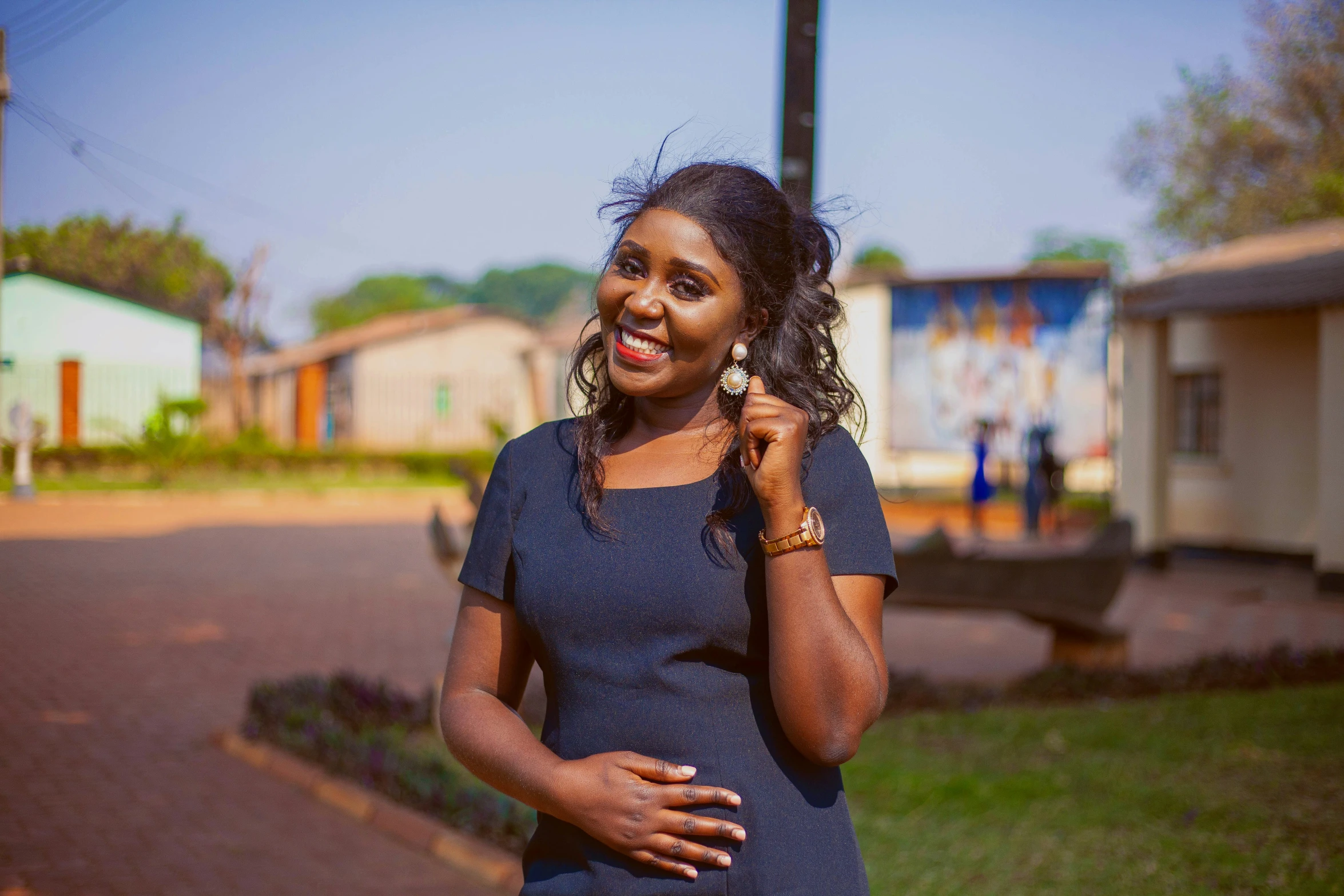 an african american woman in blue poses by a street corner