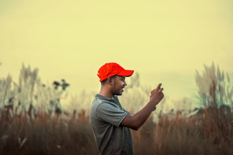 a young man is standing outside wearing a red hat