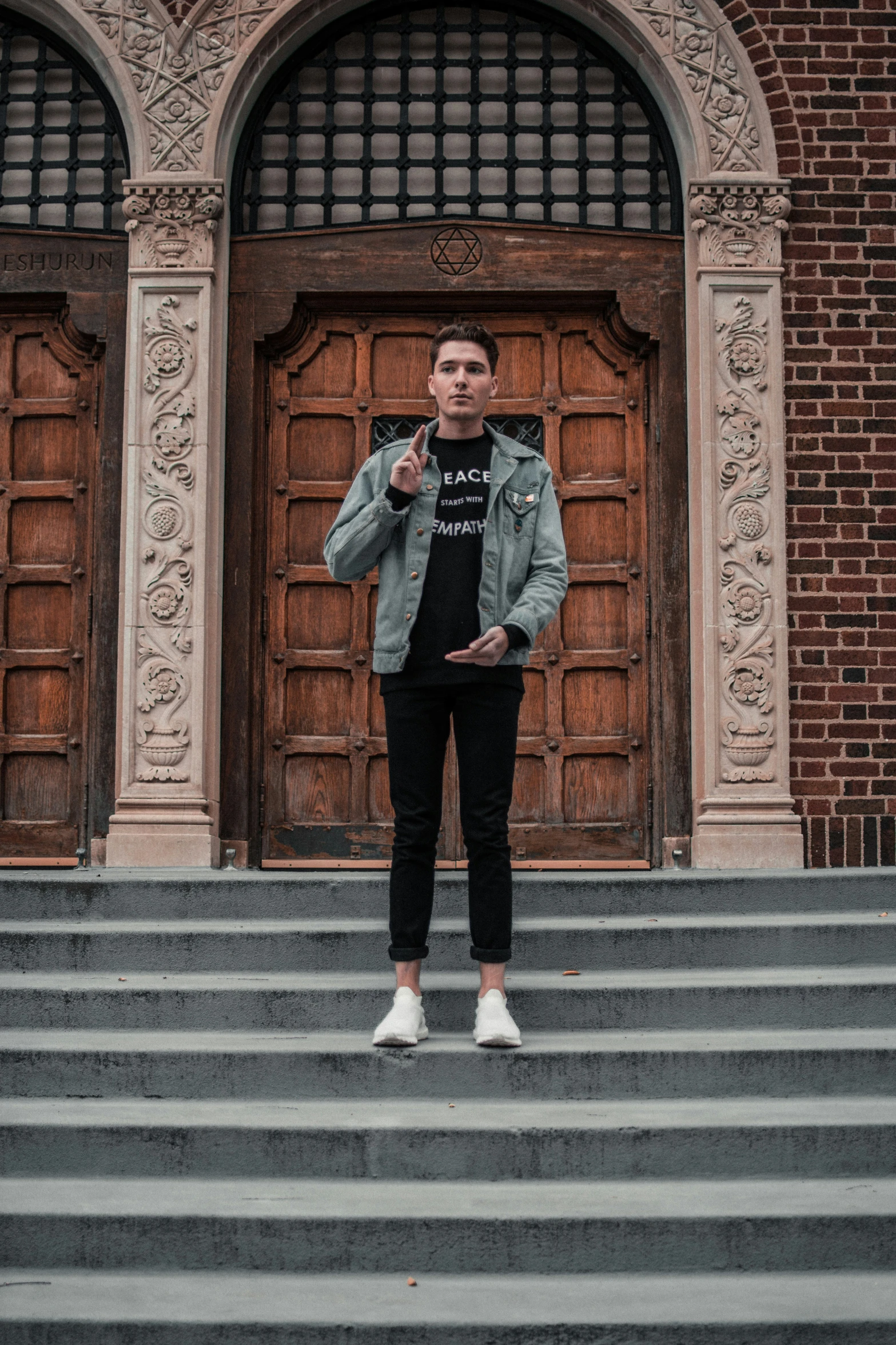 young man standing in front of brown door while talking on his phone