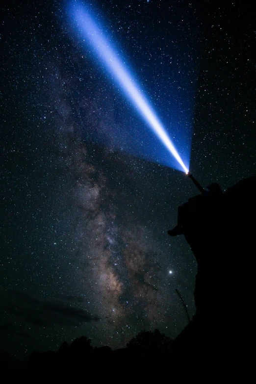 a picture taken from the side of a cliff at night of a blue star and a person holding a flashlight