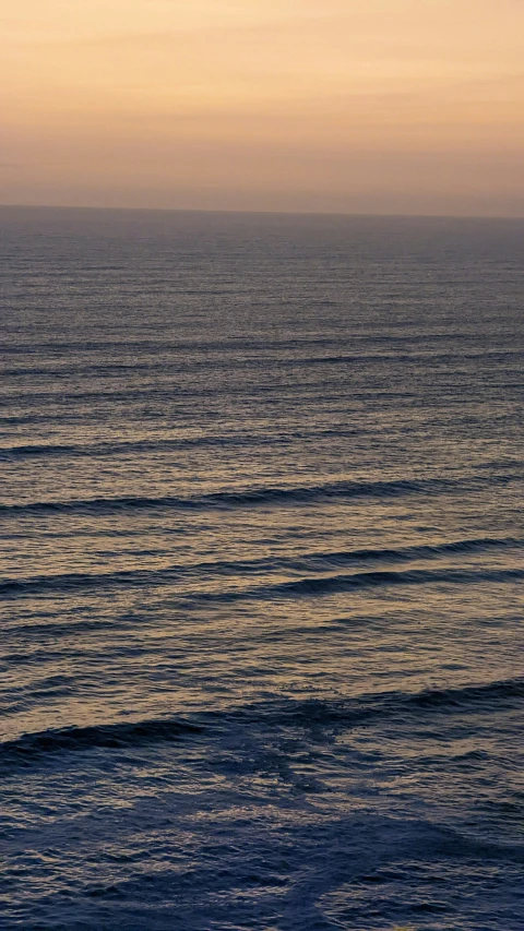 an ocean view with waves coming in and the person holding a surfboard